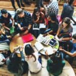 group of students gathered around coffee tables studying